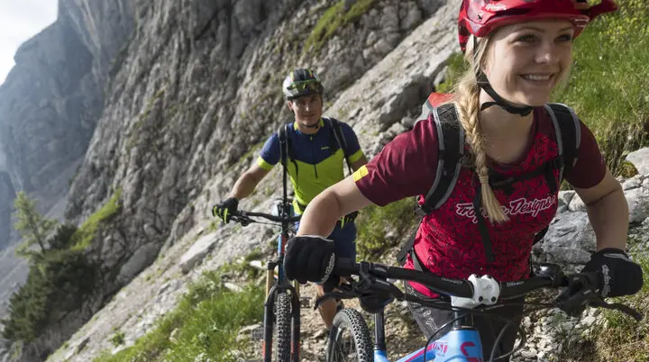 Zwei Mountainbiker*innen fahren in den Bergen an einem See entlang. | © DAV/Wolfgang Ehn
