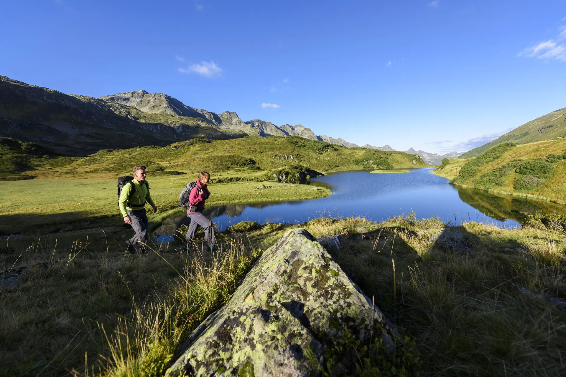 Wanderer im Frühling - im Hintergrund ein Bergsee | © DAV/Wolfgang Ehn