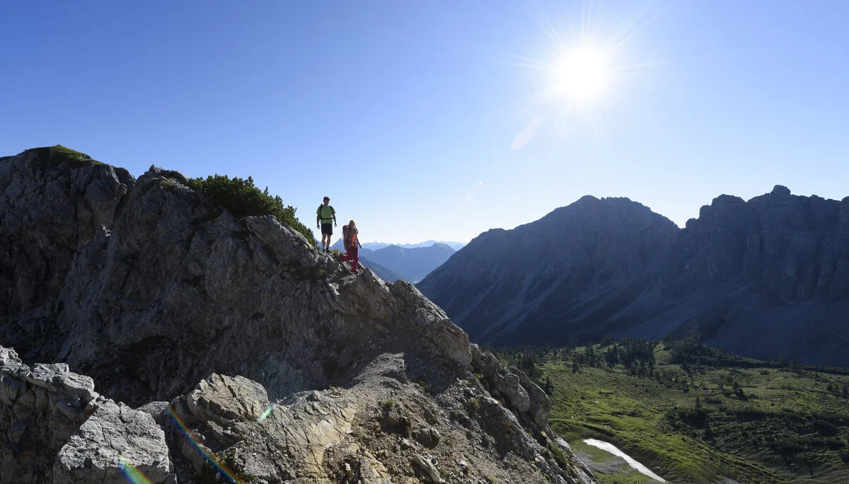Zwei Wanderer auf einem Felsgrat. Im Hintergrund grüne Bergwiesen | © DAV / Wolfgang Ehn